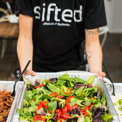 Catering Server placing a pan of lettuce on table